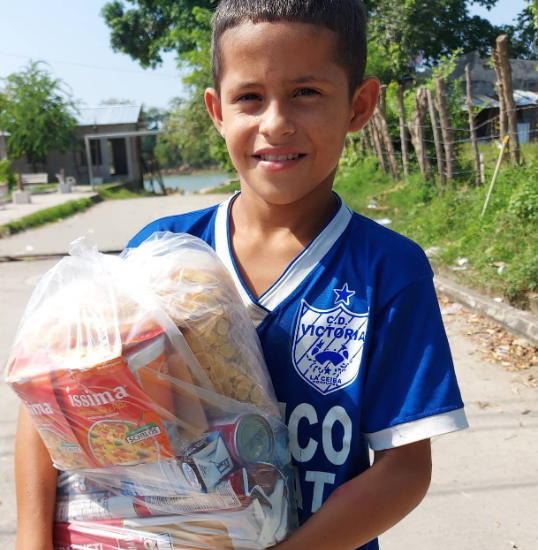 Niño hondureño recibe una bolsa de alimentos